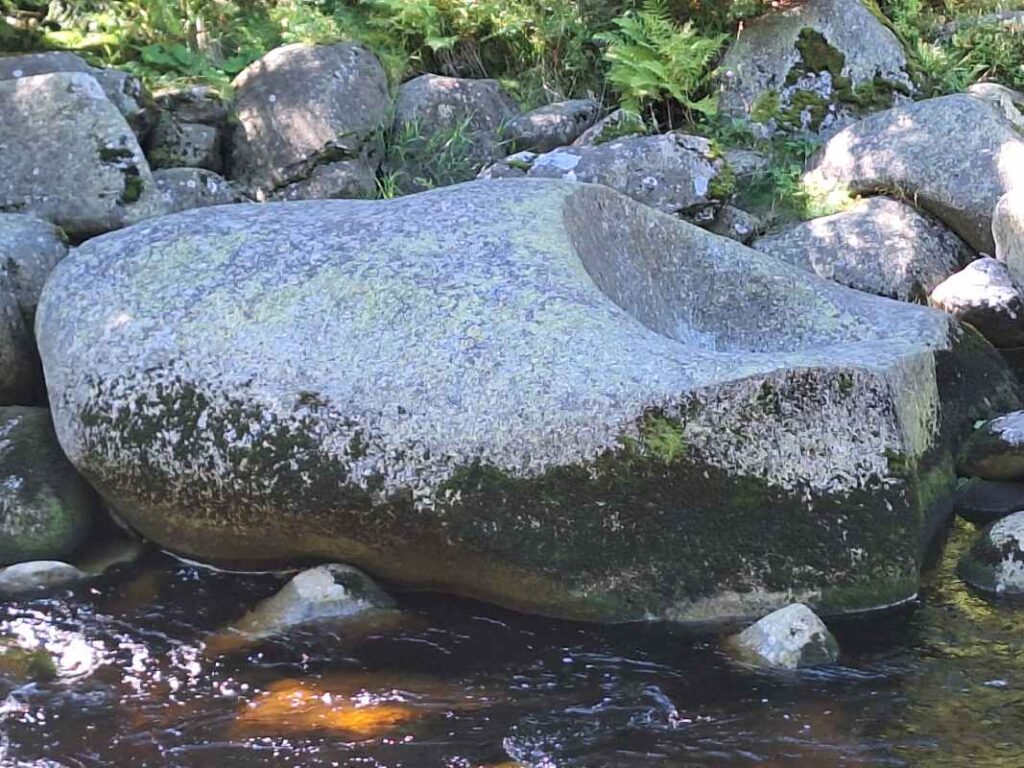 balvan ležící na kraji řeky, ohlazený vodou